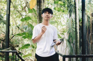 Asyalı adam düşünüyor ve doğanın geçmişi hakkında tablet tutuyor.