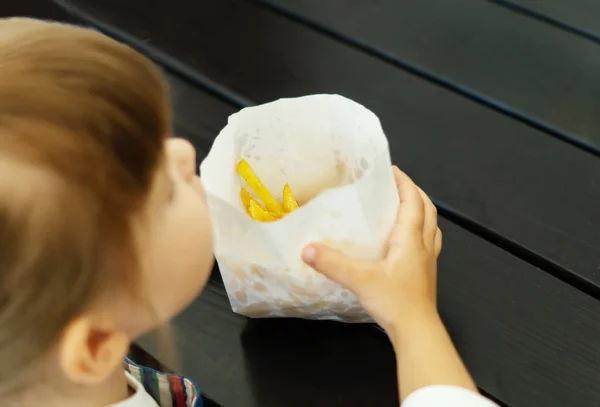 Großaufnahme Eines Hungrigen Kleinen Mädchens Mit Einer Papiertüte Pommes Einem lizenzfreie Stockfotos