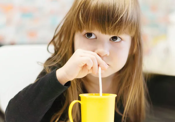 Красивая Маленькая Девочка Пьет Молоко Соломинкой Жёлтой Пластиковой Кружки Маленькая — стоковое фото