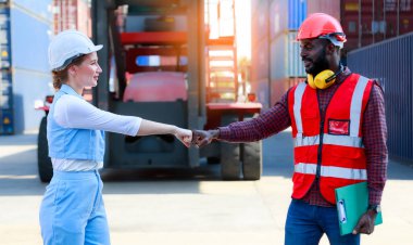 Afrika kökenli Amerikalı erkekler ve beyaz kadınlardan oluşan bir takım kask takıyor. Başarılı olayı kutlamak için tokalaşın. Kargo gemileri, ithalat, ihracat, lojistik sektörü hizmetlerinden konteynırlar.