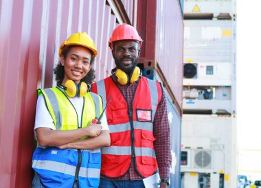 Bir kadın mühendis ve genç bir Afro-Amerikan erkek ticari bir nakliye limanındaki konteynırların yüklenmesini denetliyor ve denetliyor. Takım çalışması kavramını kullanmaktan mutluluk duyarım. İthalat-ihracat-ithalat