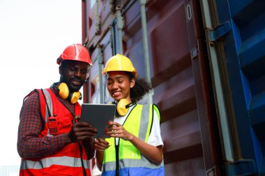 Bir kadın mühendis ve genç bir Afro-Amerikan erkek ticari bir nakliye limanındaki konteynırların yüklenmesini denetliyor ve denetliyor. Takım çalışması kavramını kullanmaktan mutluluk duyarım. İthalat-ihracat-ithalat