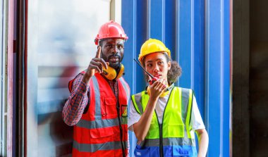 Bir kadın mühendis ve genç bir Afro-Amerikan erkek ticari bir nakliye limanındaki konteynırların yüklenmesini denetliyor ve denetliyor. Takım çalışması kavramını kullanmaktan mutluluk duyarım. İthalat-ihracat-ithalat