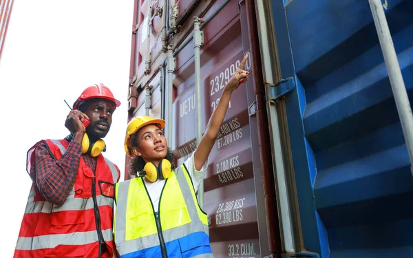 Bir kadın mühendis ve genç bir Afro-Amerikan erkek ticari bir nakliye limanındaki konteynırların yüklenmesini denetliyor ve denetliyor. Takım çalışması kavramını kullanmaktan mutluluk duyarım. İthalat-ihracat-ithalat