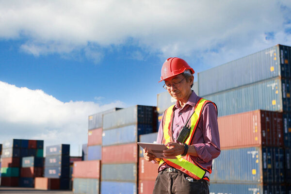 senior supervisor A man uses a tablet to control and inspect products. at the container yard for international shipping business Moving industrial goods, logistics, import-export commercial transport