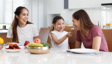 Sevimli küçük bir kız, annesinin gülümsemesi, konuşması ve gülüşüyle teyzesinin ekmeğini besliyor. Evin içindeki bir masada yemek yiyerek zaman geçir. Mutlu aile ilişkisi kavramı. Yaşam biçimi