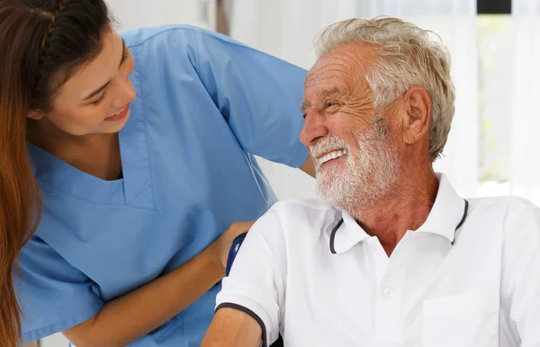 Tekerlekli sandalyedeki yaşlı beyaz bir adamla camdan bakan bir hemşire. Huzurevinin koridorunda iyi sohbetler. Sağlık konsepti yaşlanma, sağlık ve emekliliğin rehabilitasyonuna yardımcı olur.