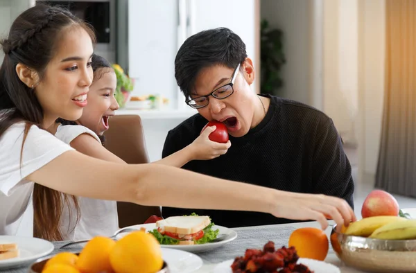 Mutlu bir Asyalı aile öğle yemeği, sebze, meyve ve tarihlerini evlerindeki masada geçirir. Tatlı küçük kız konuşuyor, eğleniyor. Baba, anne. Mutlu aile ilişkileri konsepti. Yaşam biçimi.