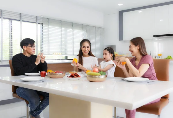 Büyük, mutlu bir Asyalı aile zamanını evin içindeki masalarda yemek yiyerek geçirir. Küçük kızım sohbet ederken eğleniyor. Babam, annem ve teyzem. Mutlu aile ilişkileri konsepti. Yaşam biçimi.