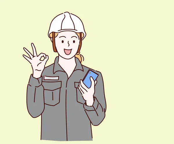 Молодая Инженер Женщина Защитным Шлемом Помощью Смартфона Показать Символический Палец — стоковый вектор