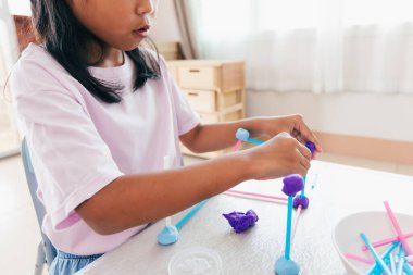 Oyun hamuru ve pipetle oynayan sevimli Asyalı kız çocuğu. Çocuk bir molekül modeli oluşturmak için oyun hamuruna odaklanmış. Çocuk ve el işi geri dönüşümlü şeyler..