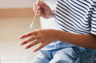 Asyalı kız çocuğu parmak yarasını temizliyor ve kaza geçirdikten sonra ilk yardımı kendi başına yapıyor..