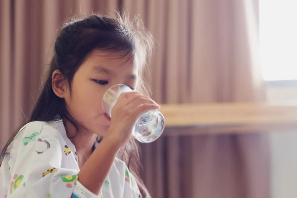 病院内の個室に滞在しながら薬を飲んで水を飲んでいる病弱なアジア系の子供 ヘルスケアとライフスタイルのコンセプト — ストック写真