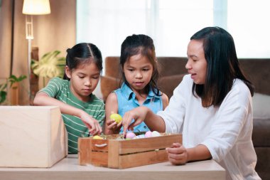 Asyalı anne ve kızları Paskalya yumurtalarını evde hazırlıyorlar. Mutlu Paskalyalar Mutlu Noeller.