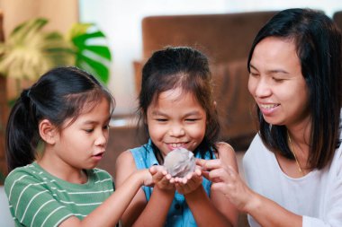Asyalı anne ve kızları yavru tavşanla oynuyorlar ve Paskalya yumurtalarını evde hazırlıyorlar. Mutlu Paskalyalar Mutlu Noeller.