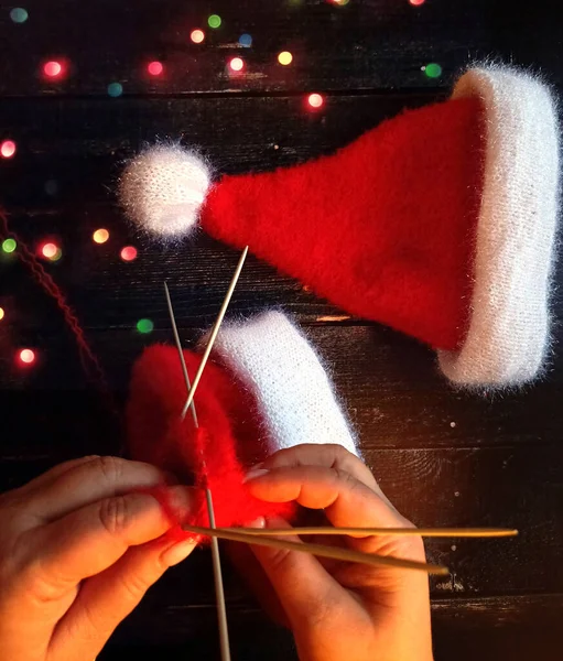 Noel 'e hazırlanan kadınların elleri, Noel Baba' ya örgü iğneli bir şapka örer.,