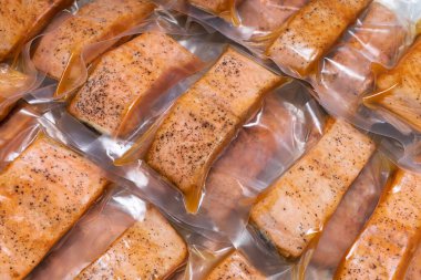 Süpürge masasında vakumlu paketlerde pişirilmiş somon balığı, yiyecek koruma kavramı, ev yemeği fikrinden iyi çalışma, bayat günde fast food, tecrit süresi için zaman kazandıran yemek.