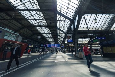Passengers commute in main station, Zurich HB, the largest railway station in Switzerland. Interior shot of Zurich Hauptbahnhof. Beautiful roof structure at daytime.
