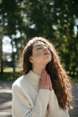 Genç esmer kadın gözleri kapalı meditasyon yapıyor.