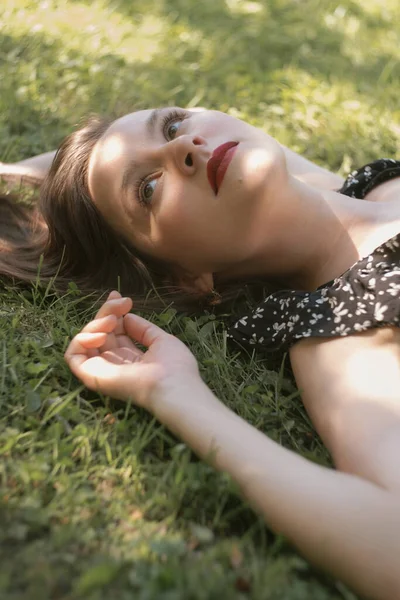 Young woman in black dress lying on green grass Stock Image