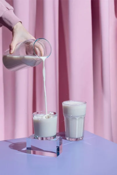 Female hand pouring homemade oat milk into a glass, plant-based milk concept Stock Picture