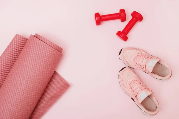 Vista superior de mancuernas, alfombra y zapatillas de deporte sobre fondo rosa. —  Fotos de Stock