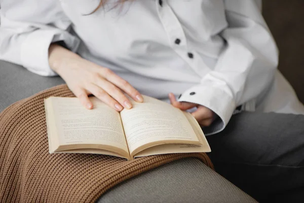 Zbliżenie kobiety trzymającej i czytającej książkę na sofie. — Zdjęcie stockowe