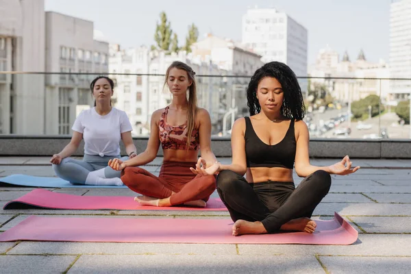 Três jovens mulheres fazendo ioga ao ar livre. — Fotografia de Stock