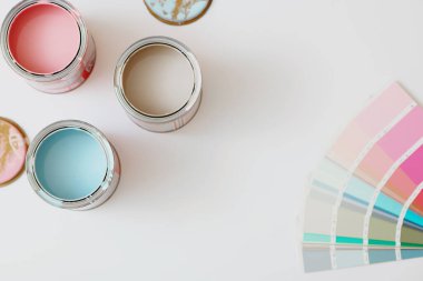 Beyaz arkaplanda boya ve renk paleti olan kutuların üst görünümü.