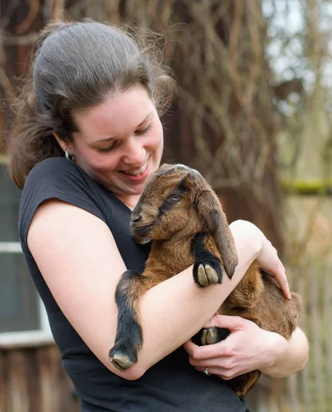 年轻的女农民 怀里抱着可爱的小山羊 — 图库照片