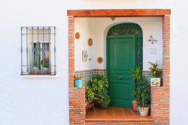 Beautiful rural door entrance with green doors and flowers.