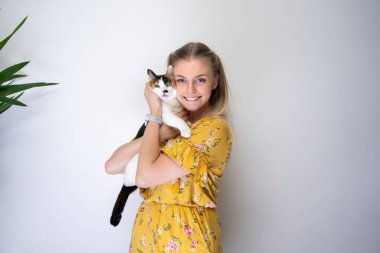 Genç sarışın kadın kedisini fotokopi aletiyle kucaklıyor.