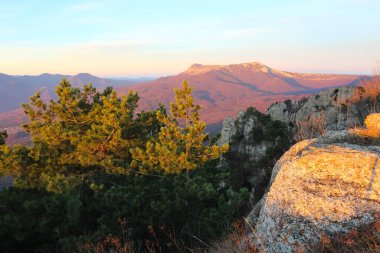 Güneşin dağlardan yükselen manzarası. Kayalıklardaki güneşten gelen turuncu refleksler.