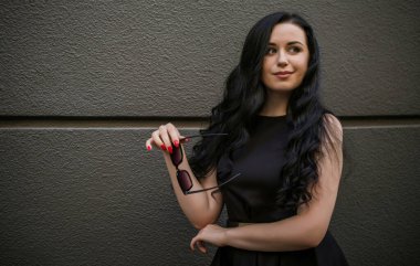 Koyu renk saçlı ve soluk tenli Avrupalı bir kadın, şehirde klasik tarzda, şık bir açık hava portresi.