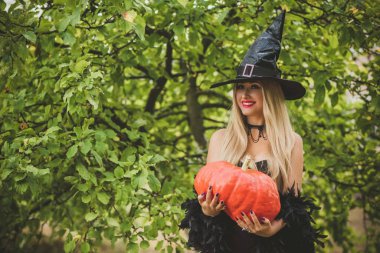 Cadılar Bayramı partisi konsepti, siyah elbiseli gizemli kız. Güzel, genç, karanlık cadı kadın. Cadılar Bayramı kutlamaları için ilham, fikirler ve basit detaylar.