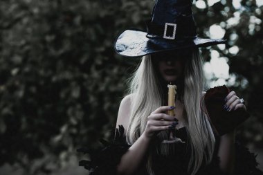 Cadılar Bayramı partisi konsepti, siyah elbiseli gizemli kız. Güzel, genç, karanlık cadı kadın. Cadılar Bayramı kutlamaları için ilham, fikirler ve basit detaylar.