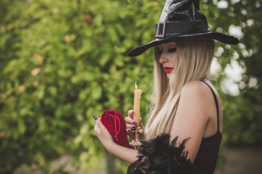 Cadılar Bayramı partisi konsepti, siyah elbiseli gizemli kız. Güzel, genç, karanlık cadı kadın. Cadılar Bayramı kutlamaları için ilham, fikirler ve basit detaylar.