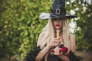 Cadılar Bayramı partisi konsepti, siyah elbiseli gizemli kız. Güzel, genç, karanlık cadı kadın. Cadılar Bayramı kutlamaları için ilham, fikirler ve basit detaylar.