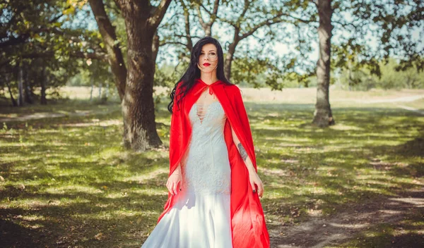 ハロウィンのコンセプト 華やかな衣装の詳細 森の中で若い美しいと神秘的な女性は 白いドレスと赤のクローク 小さな赤いフードや吸血鬼の物語 — ストック写真