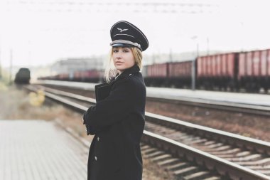 Avrupalı ya da Amerikalı tren kondüktörü bir platformda ve diğer trenlerde görevdedir. Tren yolu, buharlı trenler. Trendeki tren kontrolörü, lokomotifin yanında.