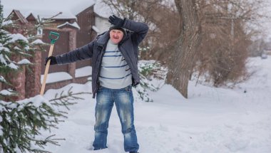 Kış, insanlar ve kar sorunu kavramı. Bahçede kürekle kar kazan adam. Mavi kürekli adam temizlik yapıyor.. 