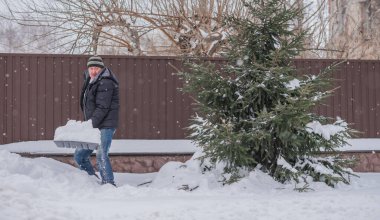 Kış, insanlar ve kar sorunu kavramı. Bahçede kürekle kar kazan adam. Mavi kürekli adam temizlik yapıyor.. 