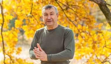 Olgun bir Avrupalı adam, güzel bir ruh hali, sonbahar parkında açık hava portresi. 50 yıl sonra yaşam konsepti