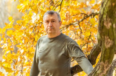 Doğada olgun Avrupalı yaşlı bir adam, sonbahar parkında felsefi bir portre,