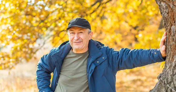 Mature European man with a good mood, outdoor portrait at autumn park . The concept of life after 50 years