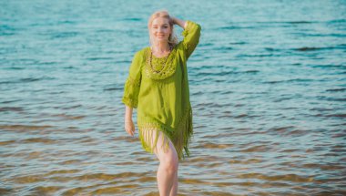 Haki keten elbiseli güzel ve iri kadın doğada dinleniyor, kadın modası konsepti. Leydi XI plajda eğleniyor.