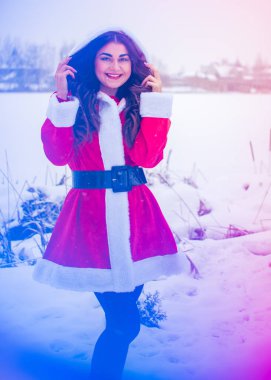 Genç Arap kadın kış günü, güzel bir Noel Baba ceketiyle karlı bir bahçede.