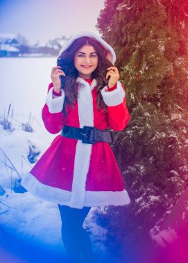 Genç Arap kadın kış günü, güzel bir Noel Baba ceketiyle karlı bir bahçede.