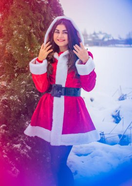 Genç Arap kadın kış günü, güzel bir Noel Baba ceketiyle karlı bir bahçede.