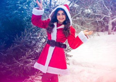 Genç Arap kadın kış günü, güzel bir Noel Baba ceketiyle karlı bir bahçede.